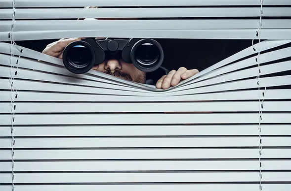 Observation durch eine Jalousie mit Fernglas
